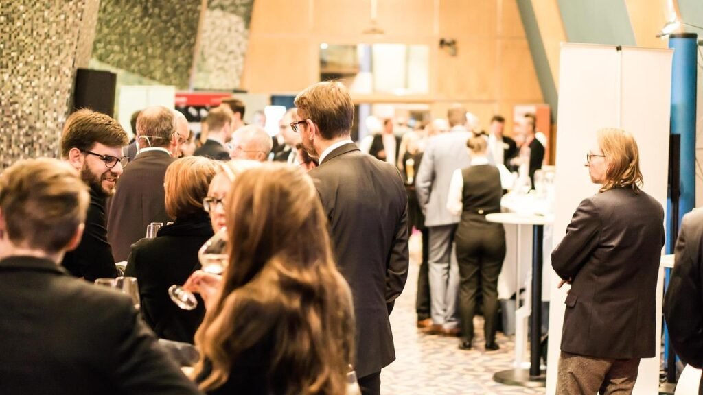 Turning Your Brand Identity Into a 3D Experience: The Case for Custom Stands Business professionals networking around custom exhibition stands at a trade show.